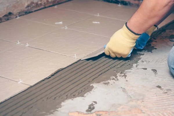 Kiris yerde sarı eldiven kare fayans ellerini koyar