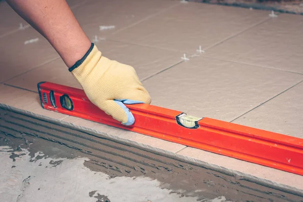 The worker uses the building level to control the quality of the finishing work