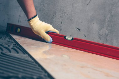 İşçi Sonlandırıcı bir bina seviyesi yardımıyla katta döşeme çalışmaları kalitesini kontrol eder