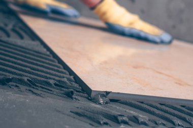 Kat, seçici odak, elinde bir kiremitçi odaklanmamış arka planda yığılmış bir taş yakın çekim