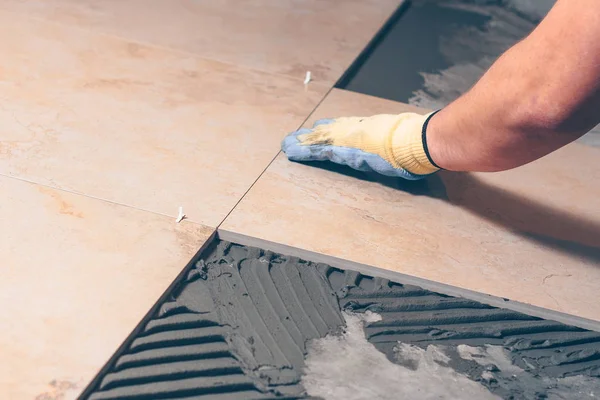 The tiler puts the tile on the floor in the classical way