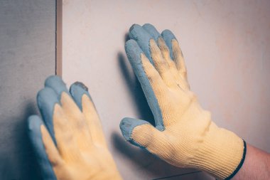 Çalışma kiremitçi çini duvara koyar, taze yapıştırılmış fayans konumunu ayarlar el, odaklanmamış, döşeme ve kaplama teknolojisi tarafından