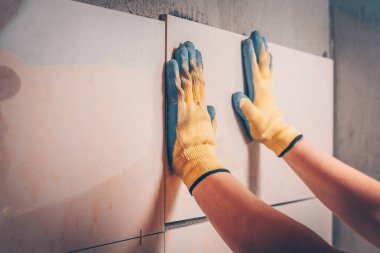 Çalışma kiremitçi çini duvara koyar, taze yapıştırılmış fayans konumunu ayarlar el, odaklanmamış, döşeme ve kaplama teknolojisi tarafından