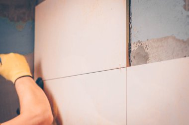 Çalışma kiremitçi çini duvara koyar, taze yapıştırılmış fayans konumunu ayarlar el, odaklanmamış, döşeme ve kaplama teknolojisi tarafından