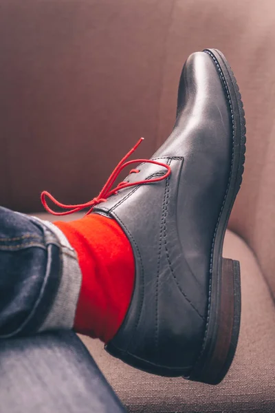 The legs of a man in shoes with red laces and in red stylish socks, fashionable shoes, a first-person view
