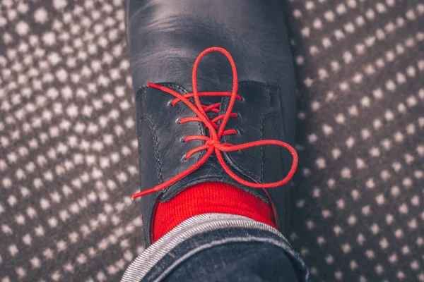 A man tries on classic leather shoes with red laces and in red stylish socks, buying shoes, a first-person view