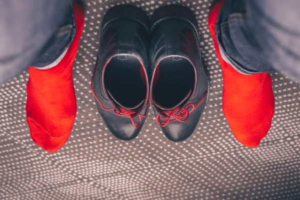 A man tries on classic leather shoes with red laces and in red stylish socks, buying shoes, a first-person view