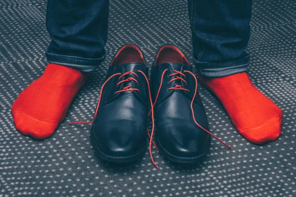 The legs of a man in shoes with red laces and in red stylish socks, fashionable shoes, a first-person view