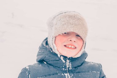 Kış karlı ve soğuk bir havada kızağa binen bir oğlanın yüzüne yakın çekim.