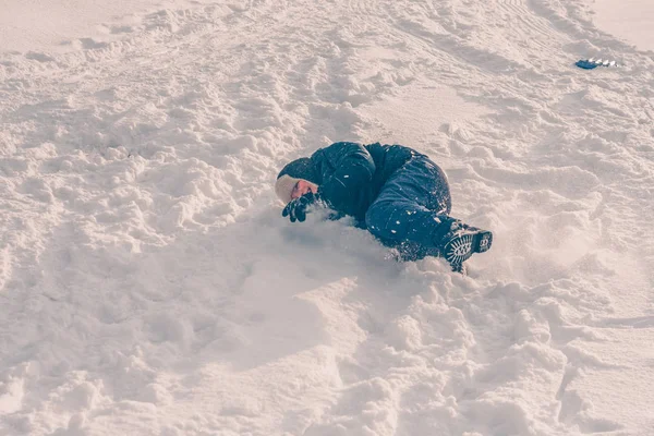 Niño Está Tirado Jugando Nieve Colina Invierno Nieve Helada Tiempo —  Fotos de Stock