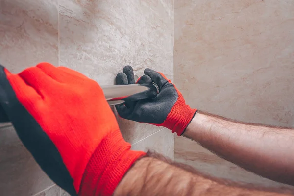 Working plumber repairs the heated towel rail in the bathroom