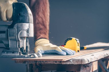 Testereden gelen talaş her yöne doğru uçuyor. İşçi yerleştirmek için laminatı kesiyor.