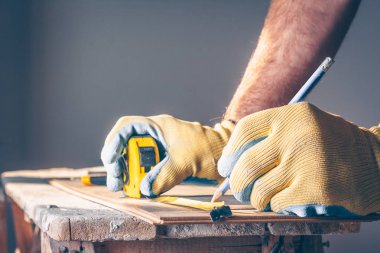 İşçi bir işaret koyar ve kaplama montaj tahtasına bir çizgi çeker.