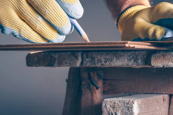 The worker places a mark and draws a cutting line on the laminate mounting board