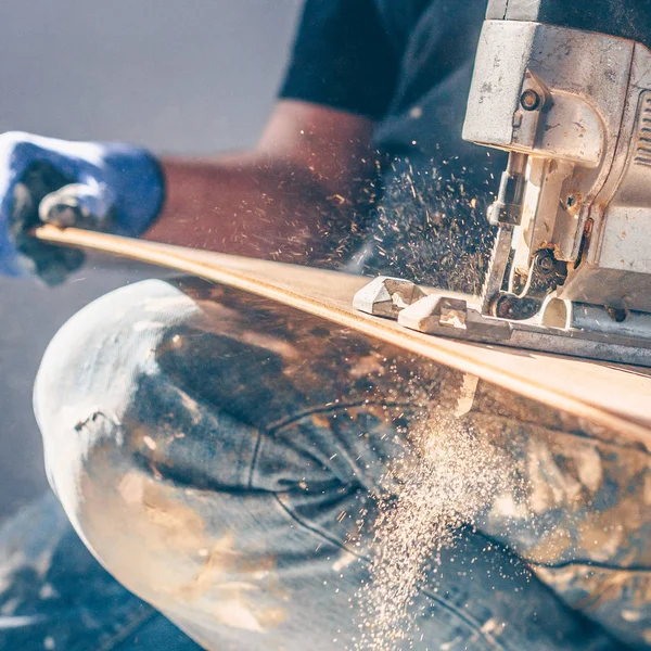 The electric jigsaw in the hands of the worker, the sawdust and dust are flying beautifully, shooting in motion