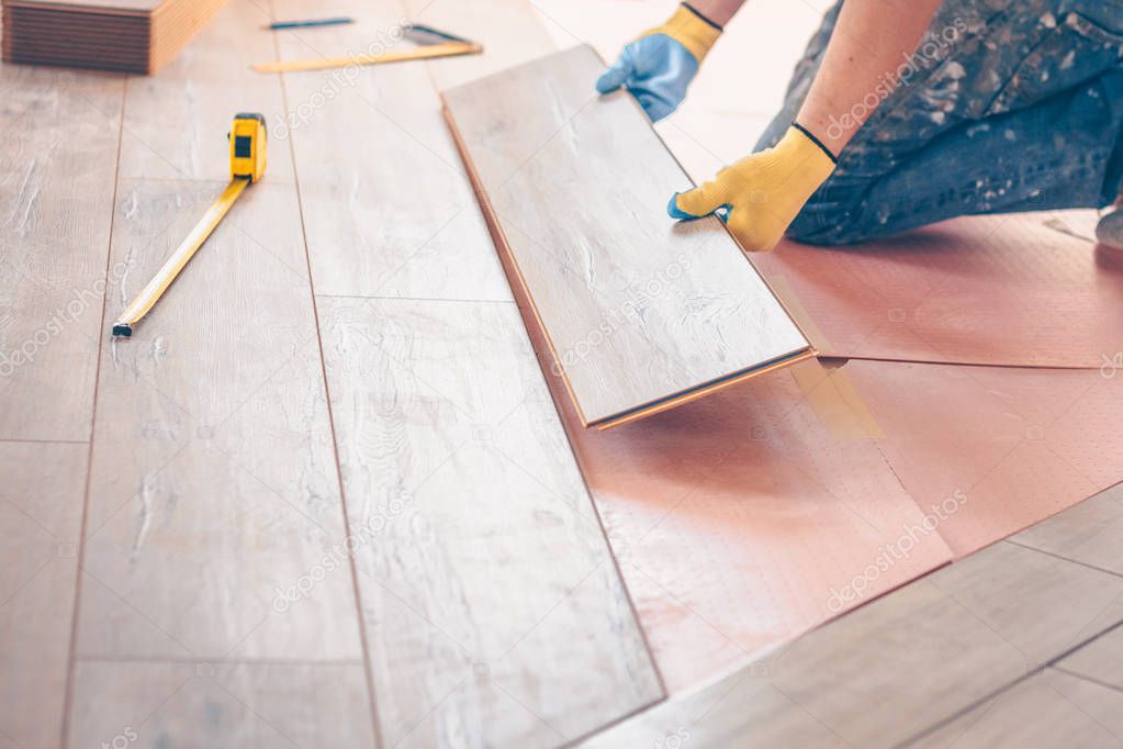 Worker professionally installs floor boards