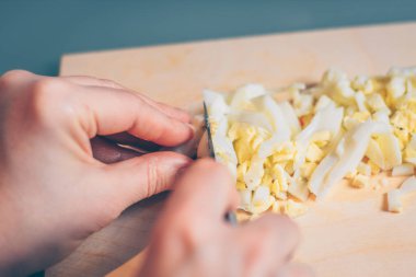 Bir kadın bir kesme tahtasında bir haşlanmış yumurta keser, bir ilk kişi görünümü