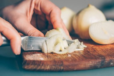 Aşçı soğanı kesme tahtasıyla keser.