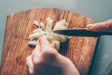 Aşçı soğanı kesme tahtasıyla keser.