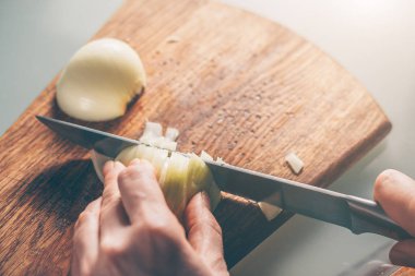 Aşçı soğanı kesme tahtasıyla keser.