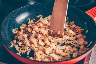 Aşçı bir tava içinde kızarmış soğan kıpırdanırken