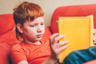 Coşku ile sevimli Kızıl saçlı çocuk kitap romanı okur