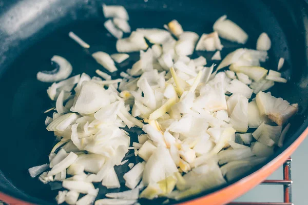 The cook pours the chopped onion into the pan