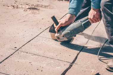 Bir işçi eve bir su borusu ve elektrik kablosu koymak için asfalt keser