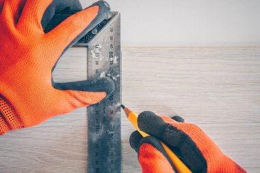 Birinci şahıs görünümü: kare ve kalem ile eldiven işçi laminat panel için bir kesme hattı uygular