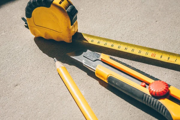 Tools for construction and finishing works: a knife, tape measure, pencil