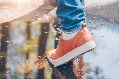 Yavaşça deri ayakkabılarında su birikintisi üstesinden gelir