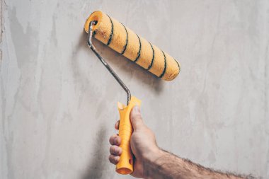 İşçi bir boya silindiri ile demontaj için eski duvar kağıdı nemlendirir
