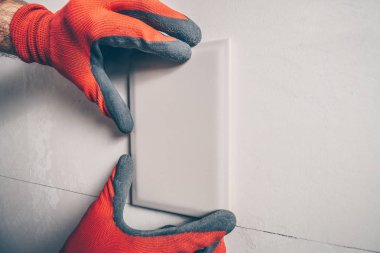 İşçi döşemeden önce duvarda yeni bir kiremit üzerinde çalışır