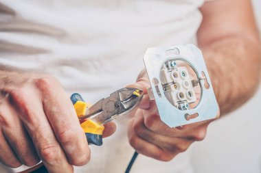 Elektrikçi, elektrik kablosunu elektrik prizine takarak elektrik iş pençesi gerçekleştirir