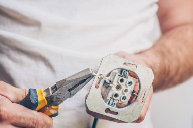 Elektrikçi, elektrik kablosunu elektrik prizine takarak elektrik iş pençesi gerçekleştirir