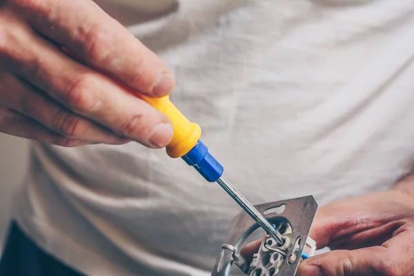 The electrician performs electrical work - connects the wires to an electrical outlet