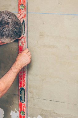 bitirme işleri-bir işçi lazer bina seviyesi kullanarak bir duvar işaretler