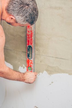 bitirme işleri-bir işçi lazer bina seviyesi kullanarak bir duvar işaretler