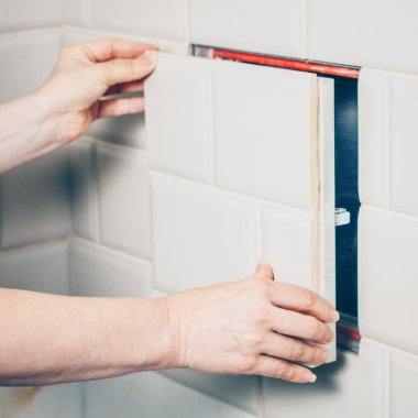 Kız tıkanma ve Temizleme ortadan kaldırmak için kanalizasyon borusunun muayene deliğe erişmek için fayans duvarında gizli bir ambar açar