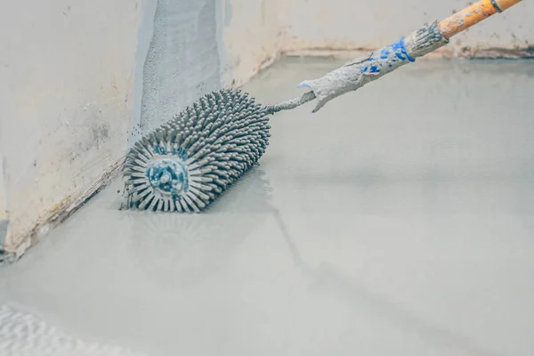 finishing work - the worker makes the floor floor with a needle roller