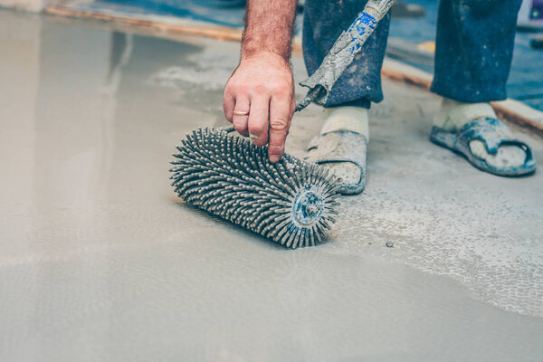 finishing work - the worker makes the floor floor with a needle roller