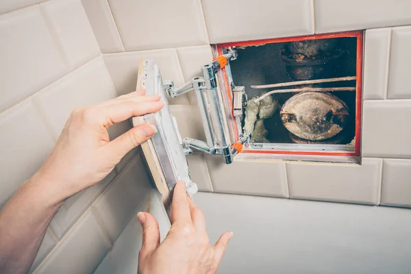 Open sanitary hatch on the wall of the tile opens access to the plumbing and sewer systems at home