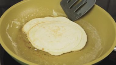 Bir mutfak spatula ile bir aşçı hamur dışarı tava yapma kahvaltı üzerinde pancake döner