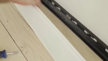 Montaj ve plastik zemin Kaide montajı teknolojisi-Işçi parke zemin üzerinde plastik bir kaide bağlar