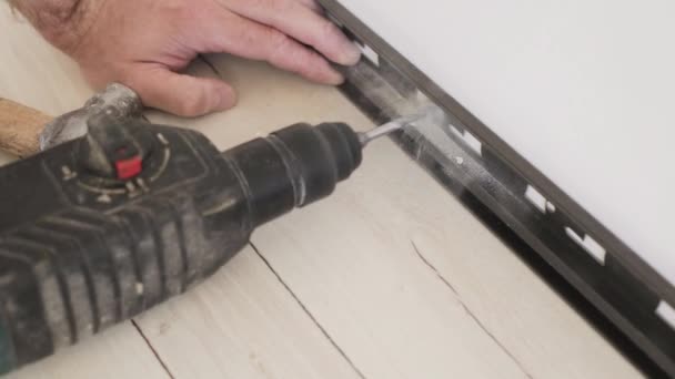 Technology installation and installation of plastic floor plinth on a concrete or stone wall - Master drills a hole in the wall using a Corded Hammer Drills — Stock Footage Technology Installation Installation Plastic Floor Plinth Concrete Stone Wall Master Stock Video