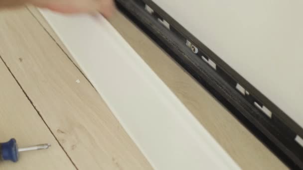 Technology of installation and installation of plastic floor plinth - Worker mounts a plastic plinth on the parquet floor — Stock Footage Technology Installation Installation Plastic Floor Plinth Worker Mounts Plastic Plinth Royalty Free Stock Video