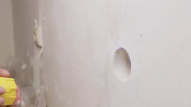 Elektrikçi, elektrik prizine monte etmek için duvardaki deliğe plastik bir fiş ekler