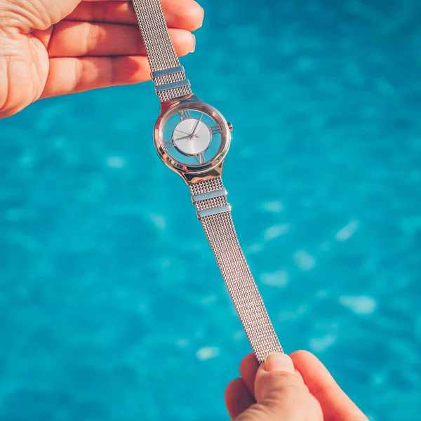 Beautiful watch in the hands of a girl against the background of water
