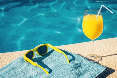 Havuzda güneş gözlüğü, havlu ve meyve suyu - tatil nitelikleri