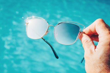 Havuzun arka planında moda gözlükleri var.